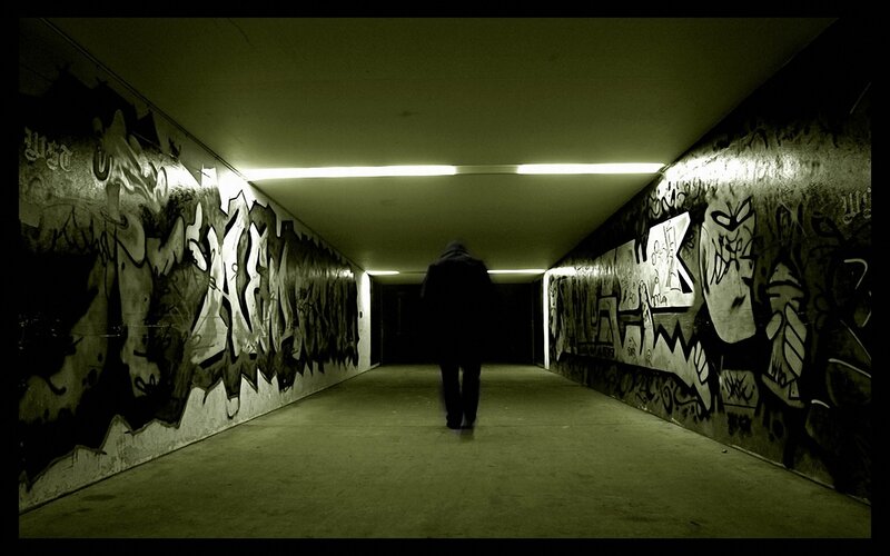 person walking through graffiti tunnel