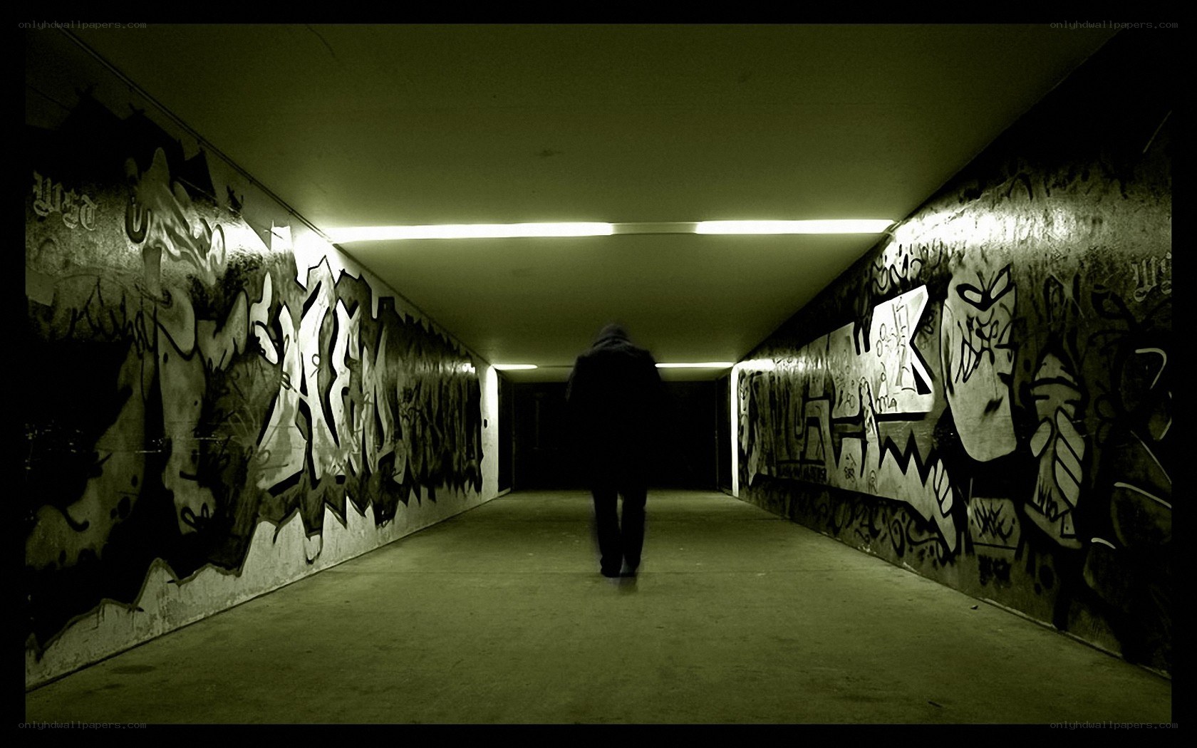 person walking through graffiti tunnel
