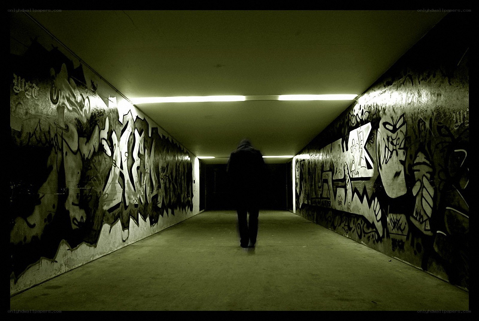 person walking through graffiti tunnel