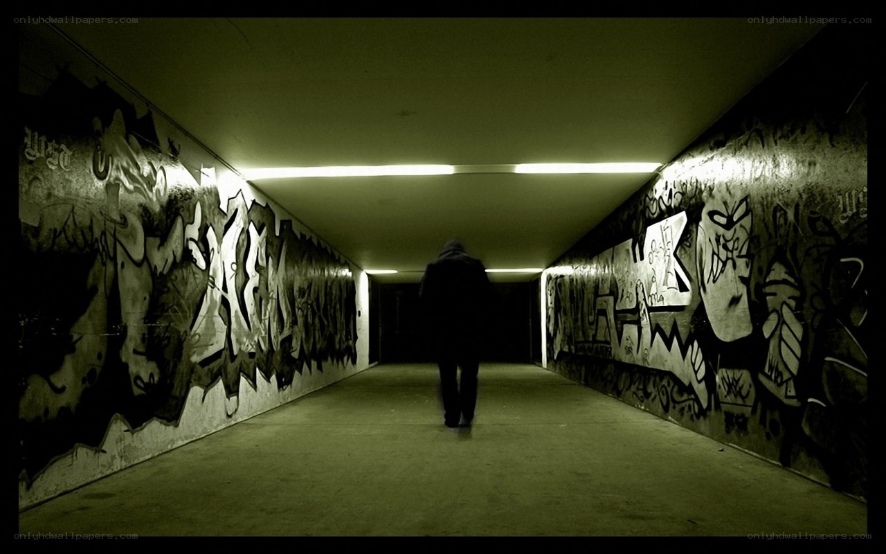 person walking through graffiti tunnel