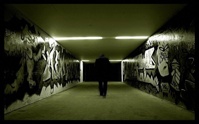 person walking through graffiti tunnel