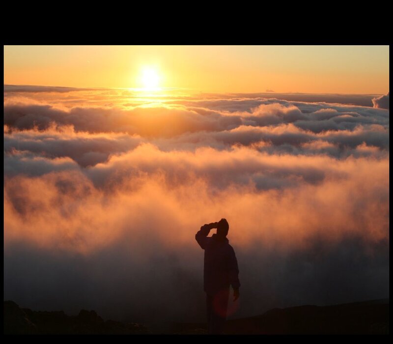 Person watching sunrise above clouds