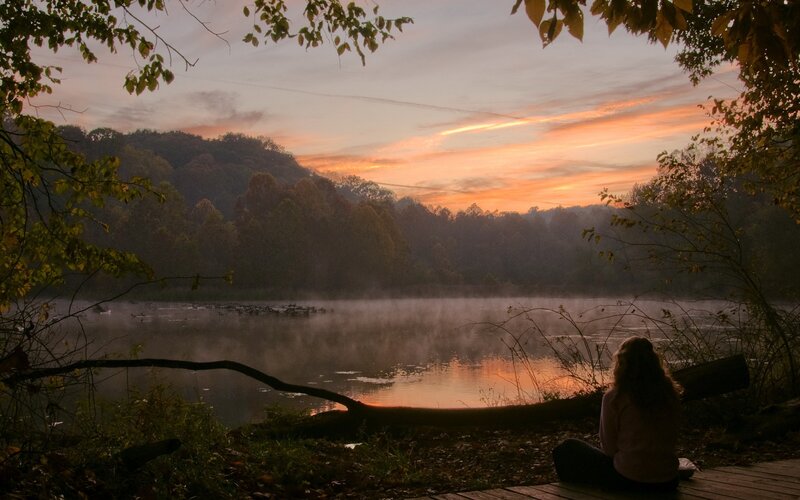 Person watching sunset at a misty lake