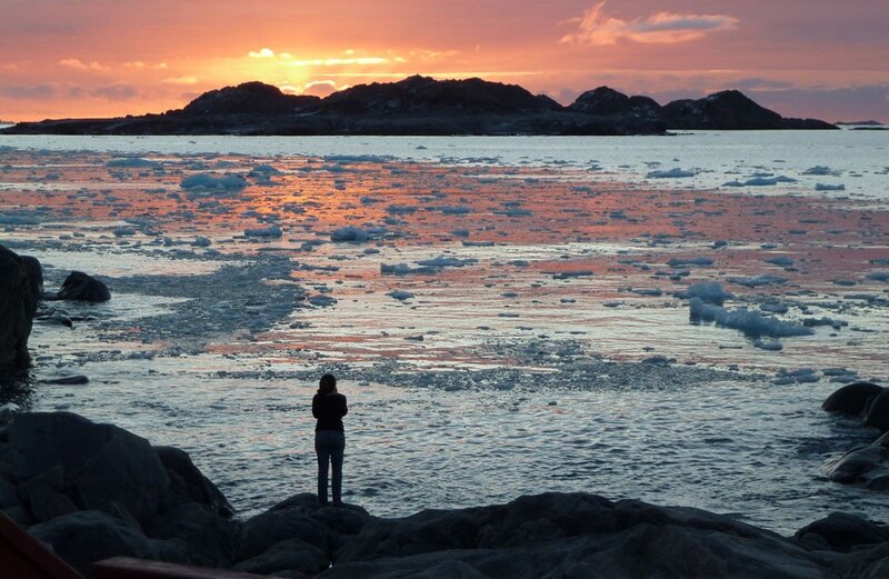 Person watching sunset over icy water