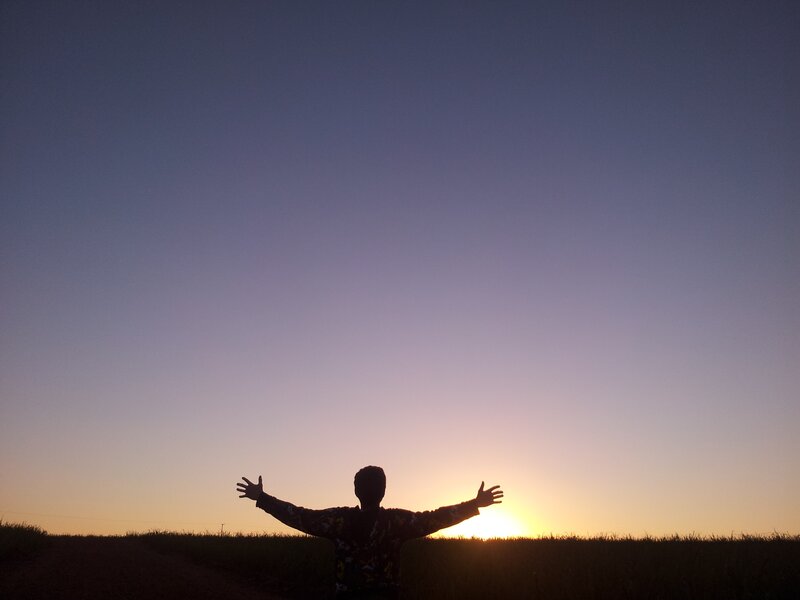 person with arms outstretched at sunset