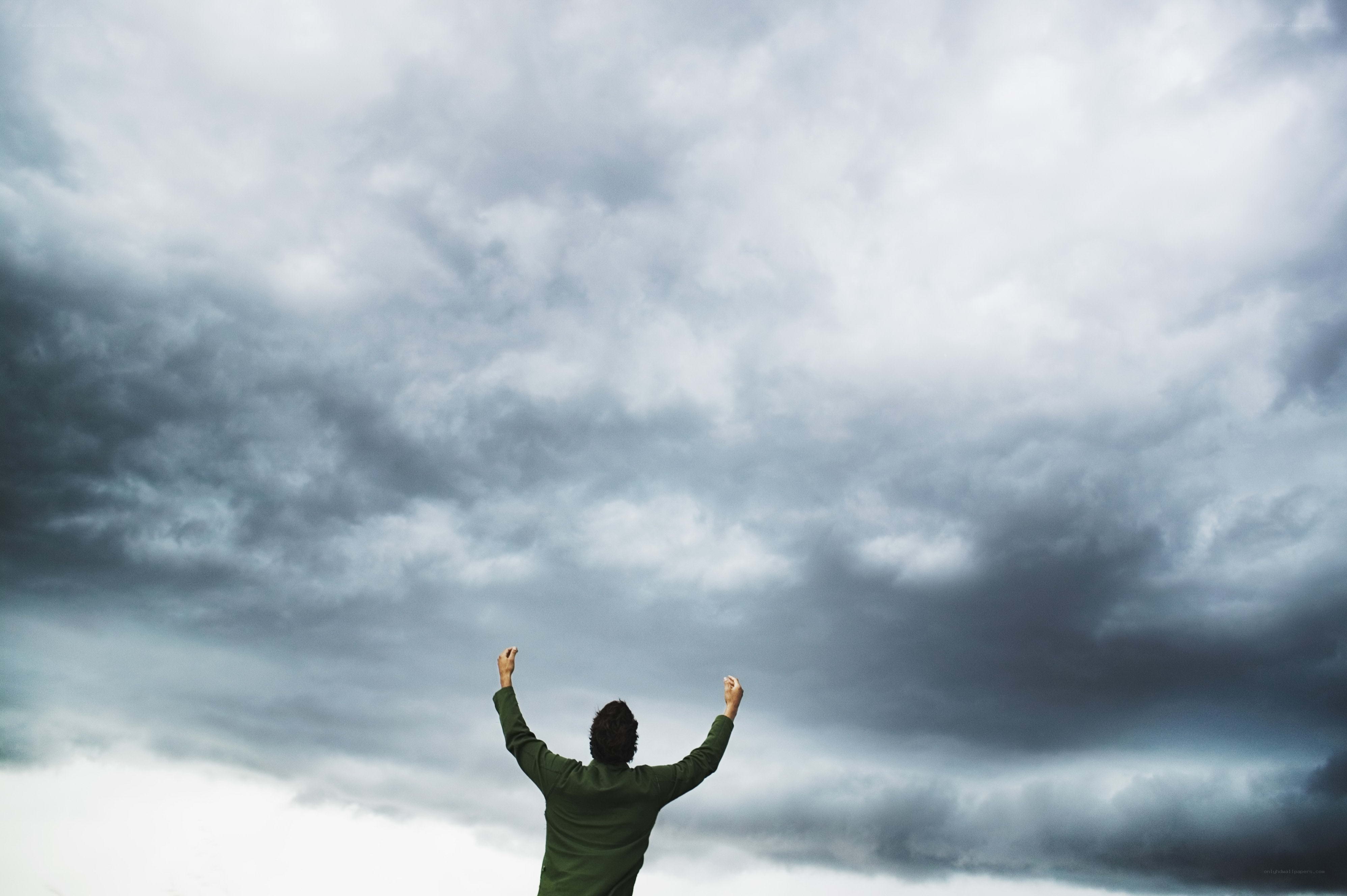 Person with arms raised to stormy sky