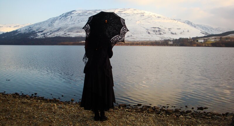 person with black umbrella by lake