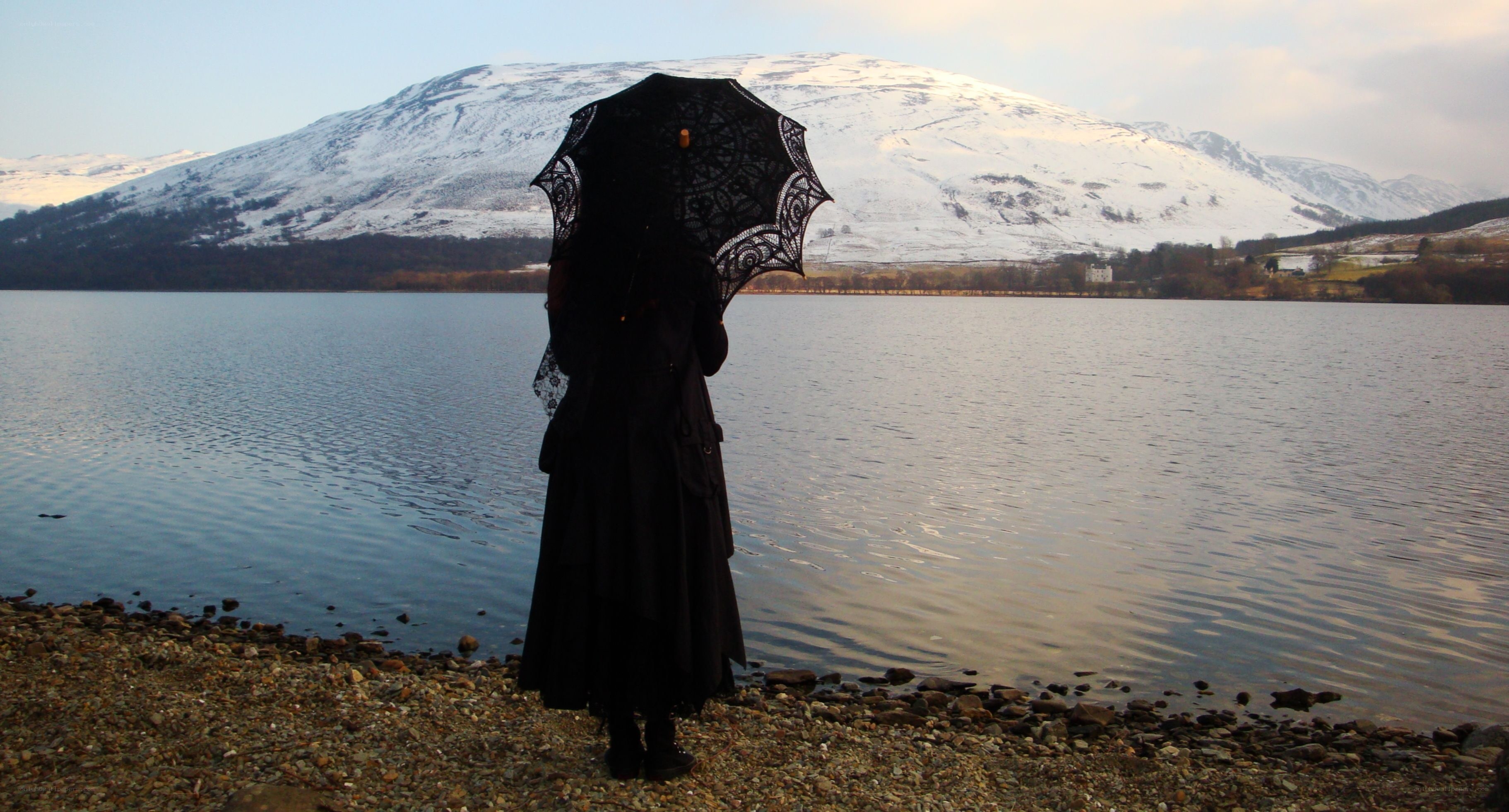 person with black umbrella by lake