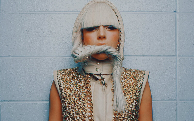 person with braided hair and studded vest