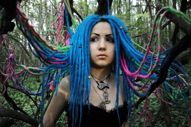 person with colorful dreadlocks in forest