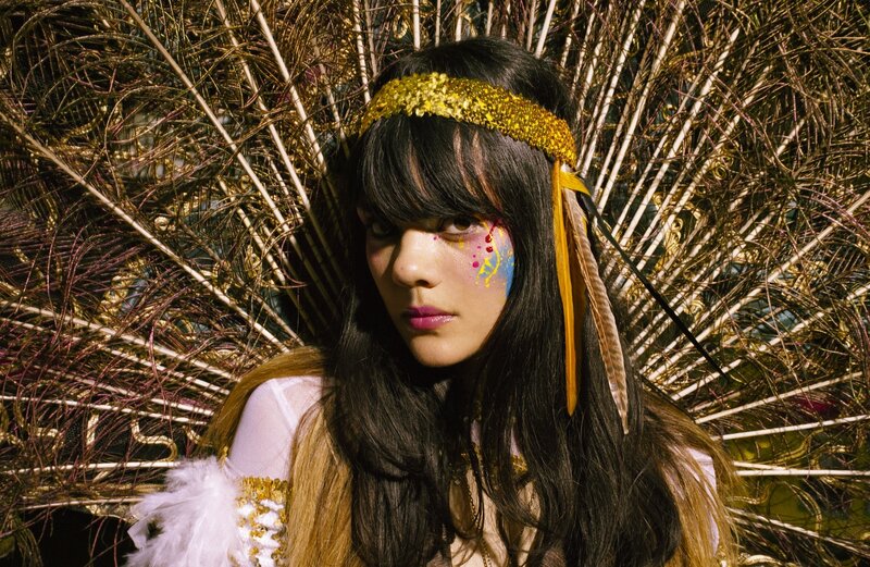 person with colorful face paint and feather headdress