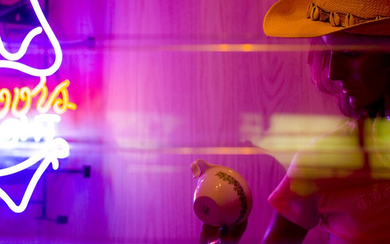 Person with cowboy hat and neon sign