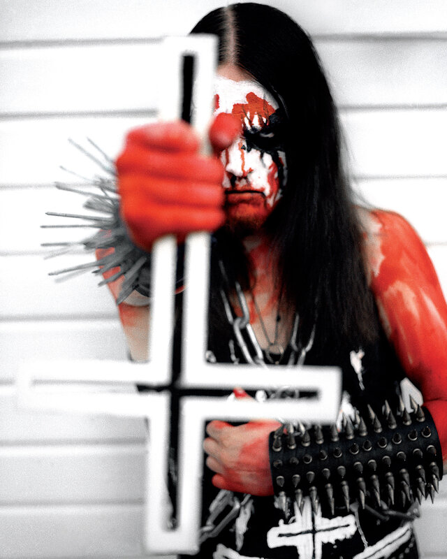 person with face paint holding cross