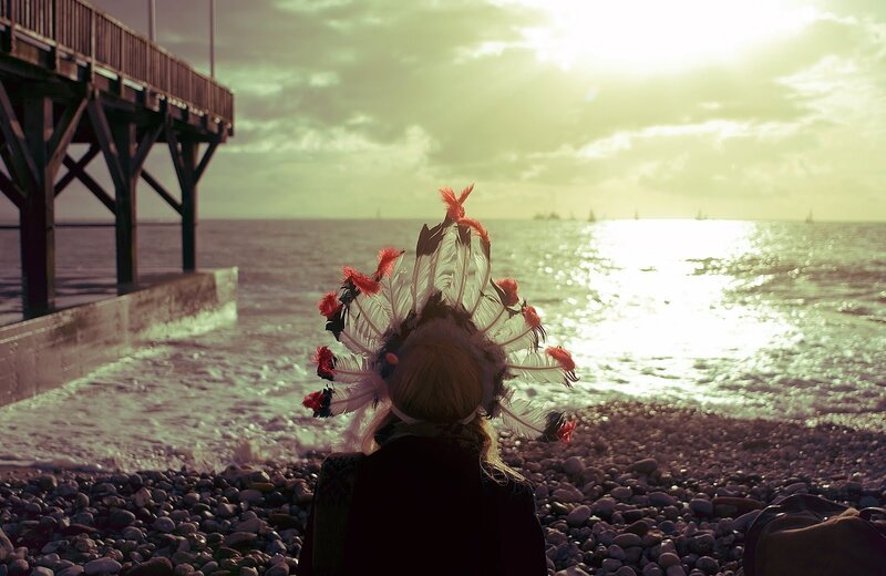 Person with feather headdress on beach