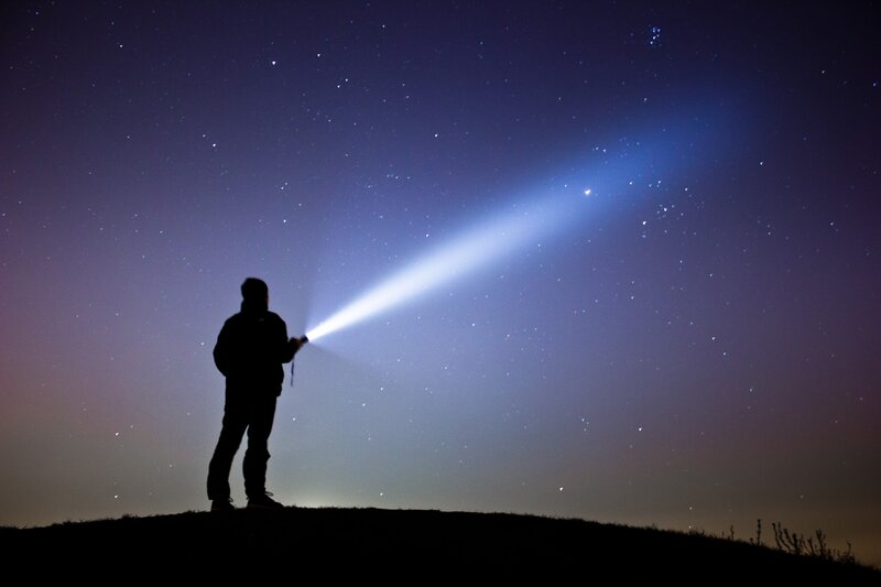 Person with flashlight under stars