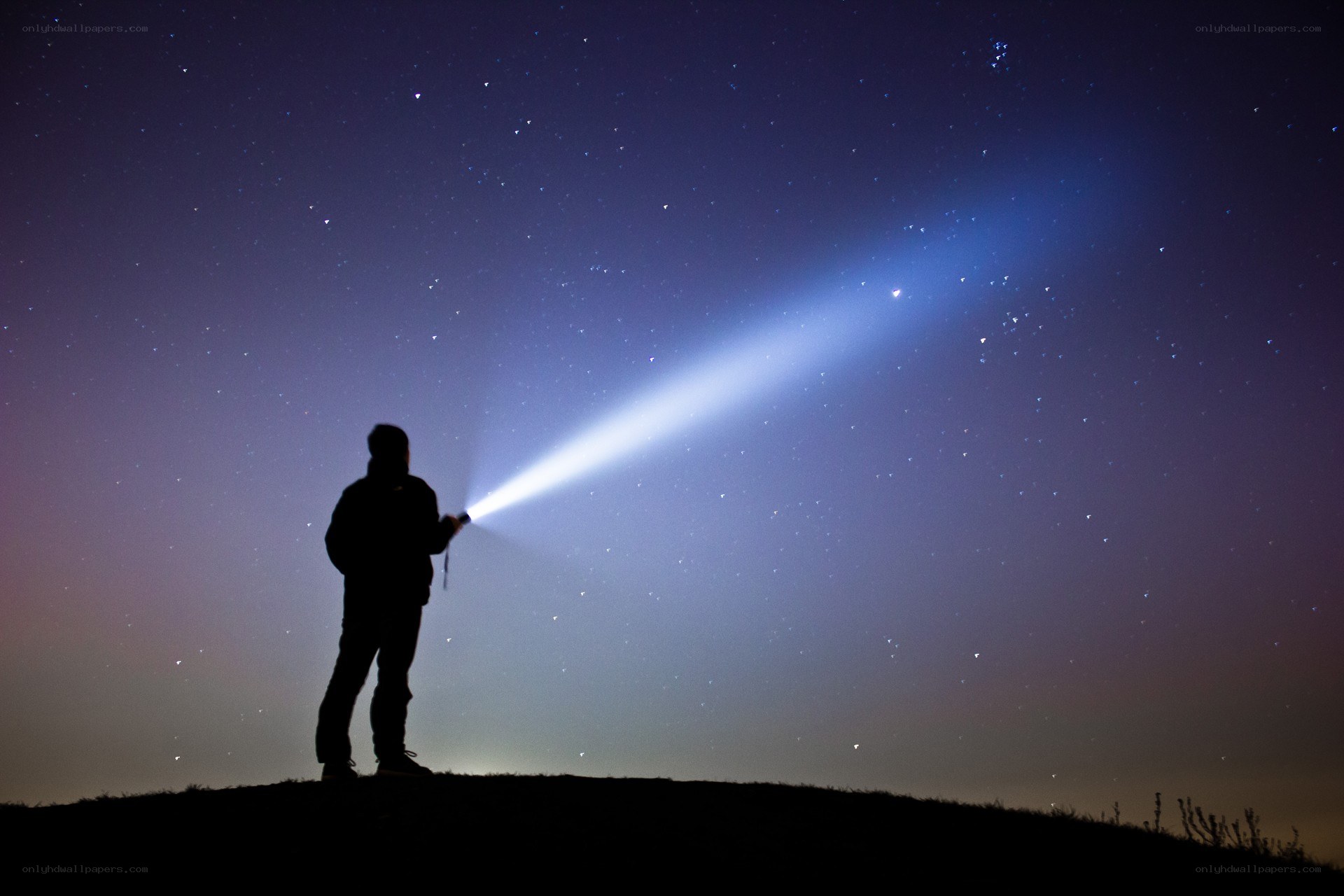 Person with flashlight under stars