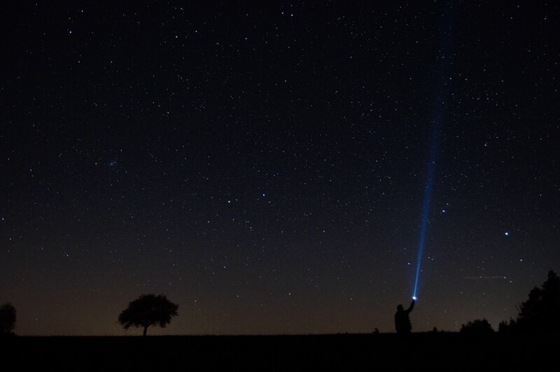 Person with flashlight under stars