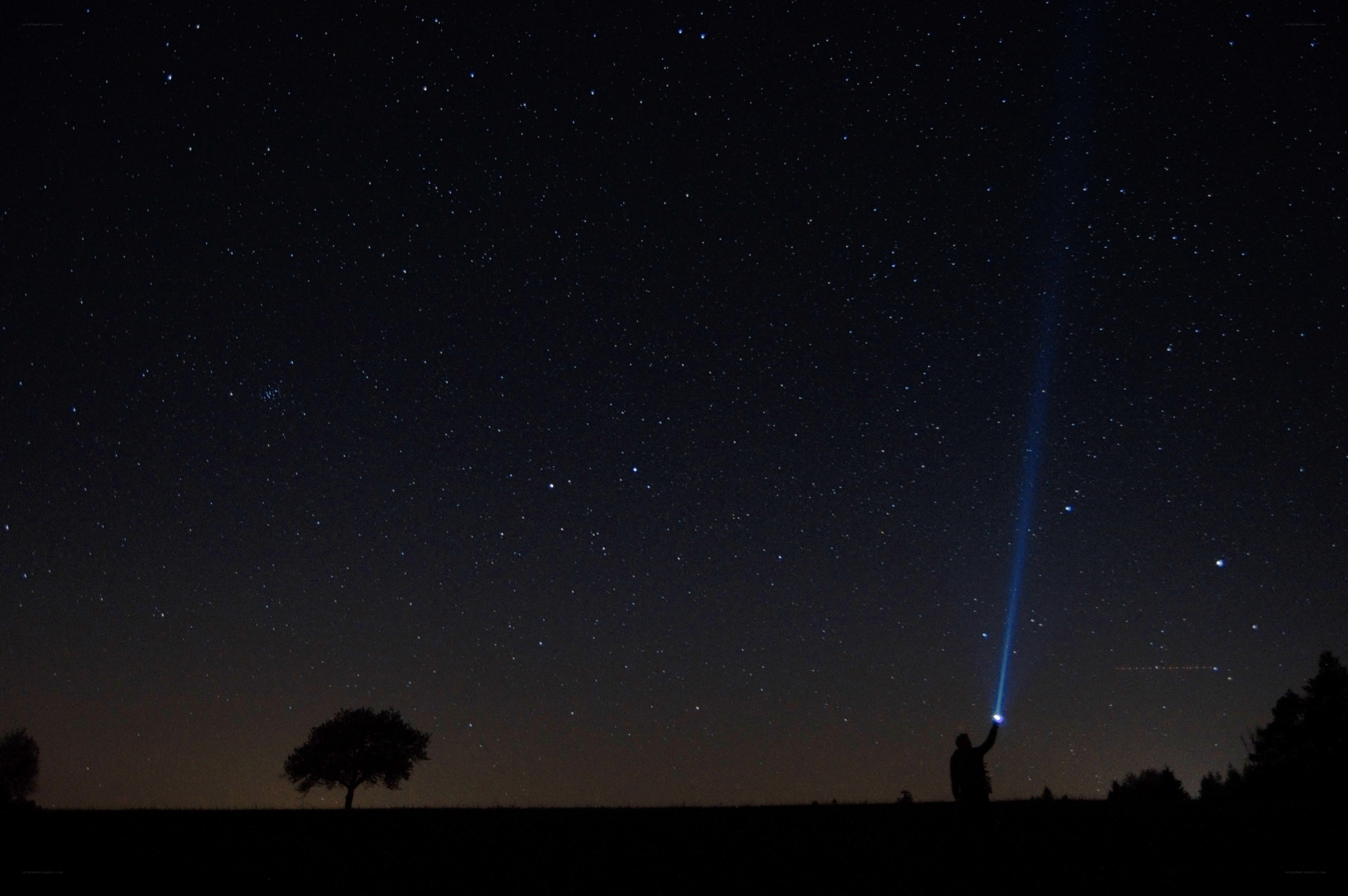 Person with flashlight under stars