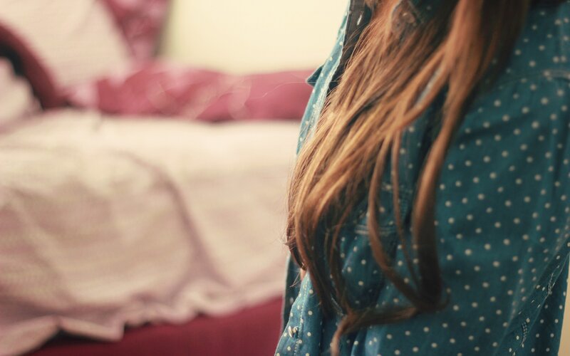 person with long hair in bedroom