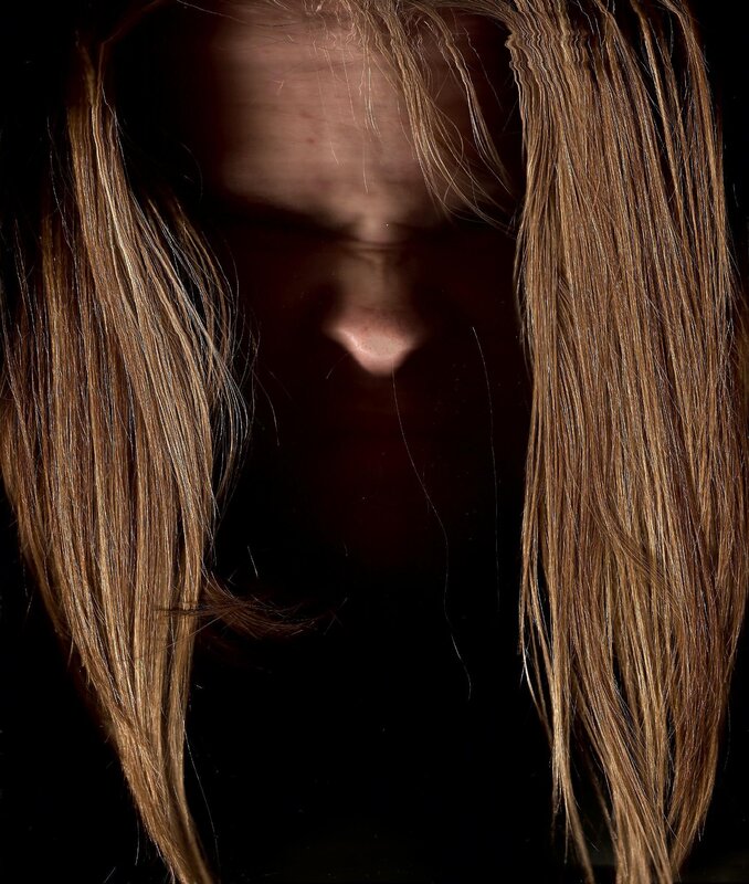 person with long hair in darkness