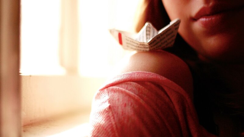 person with paper boat near window