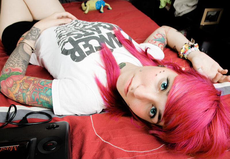 person with pink hair lying on bed