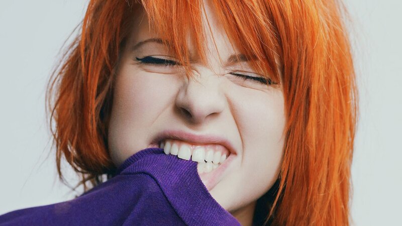 person with red hair biting shirt