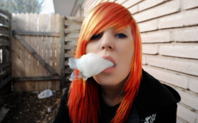 person with red hair blowing bubble gum