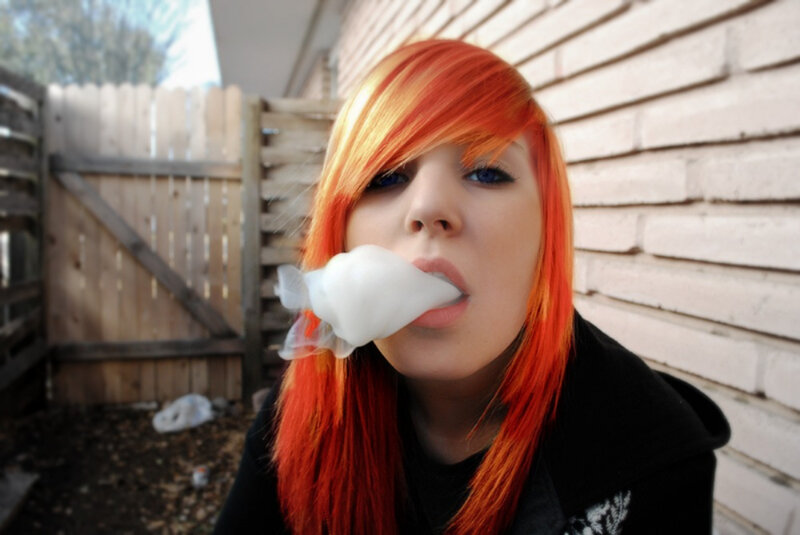 person with red hair blowing cotton candy