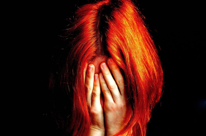 person with red hair covering face