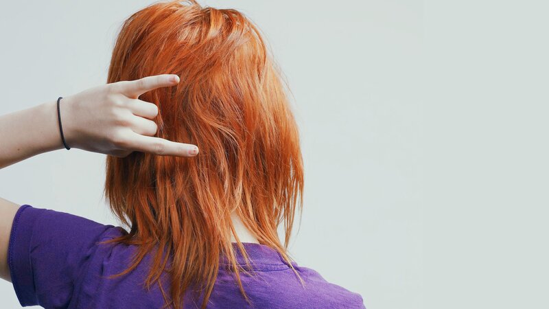 person with red hair making hand gesture