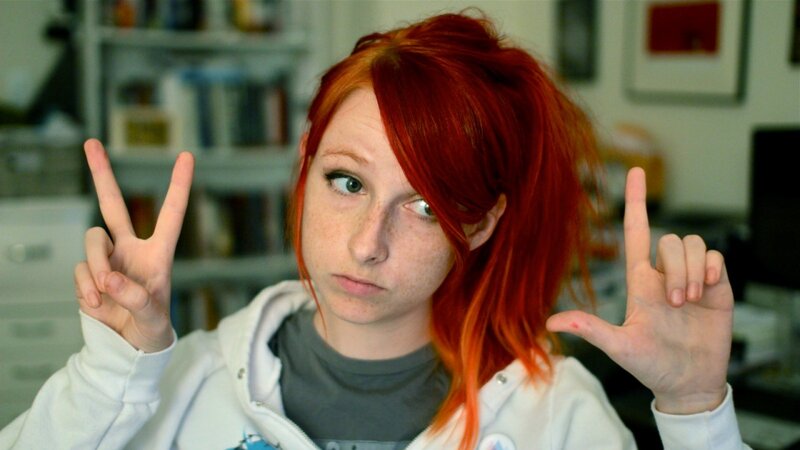 person with red hair making hand gestures