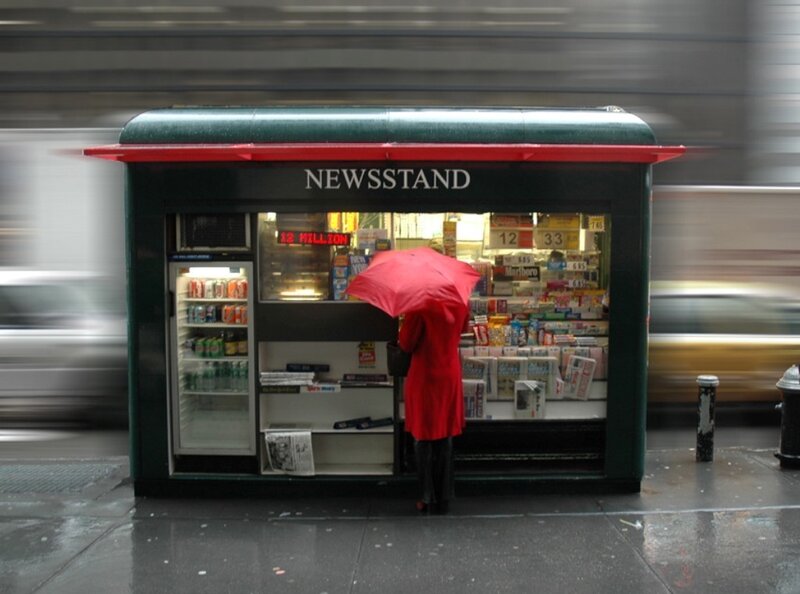 Person with red umbrella at newsstand