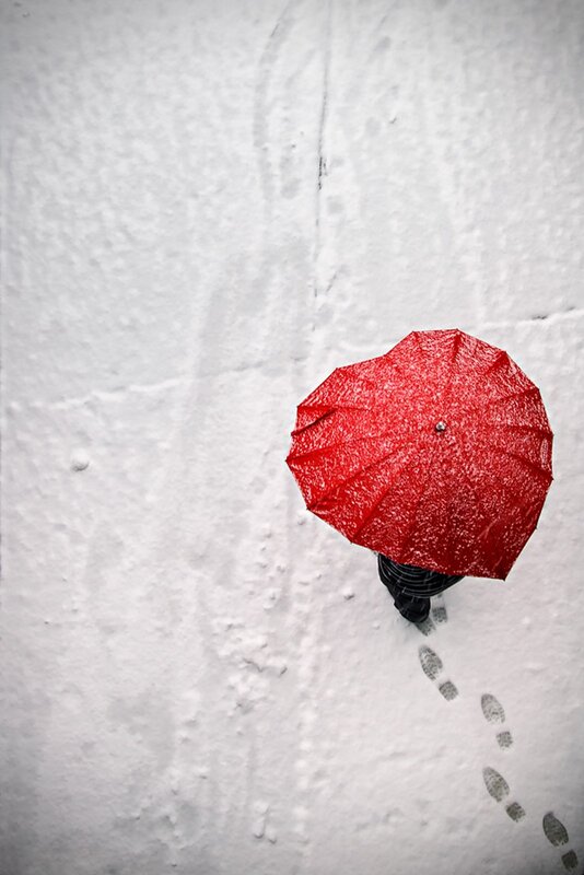 person with red umbrella in snow