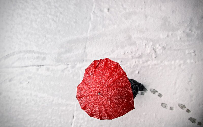 person with red umbrella in snow