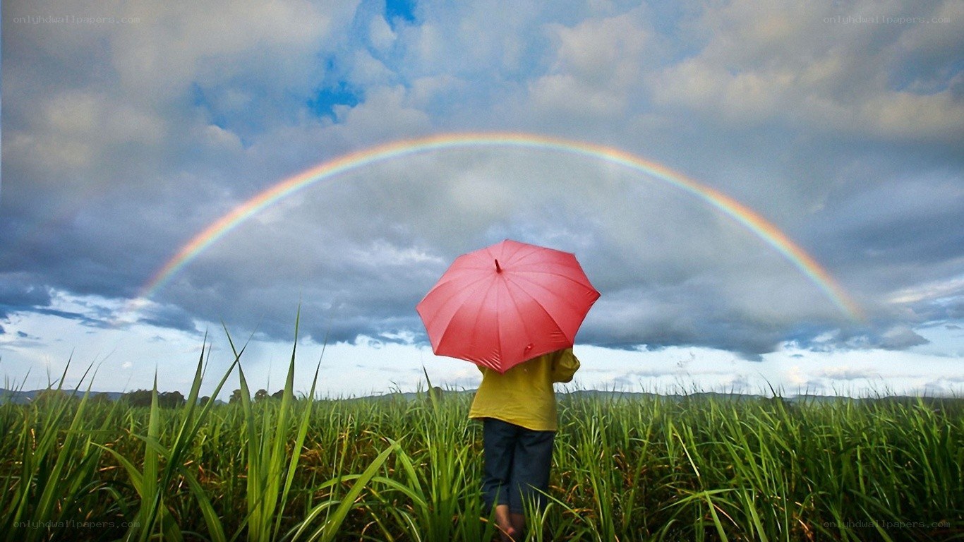 Person with red umbrella under rainbow
