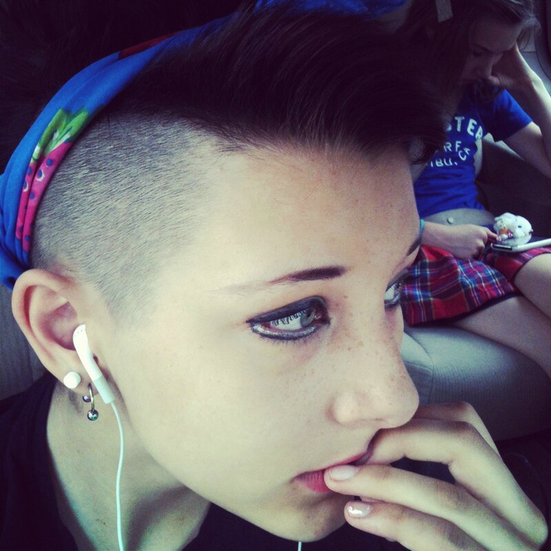 person with shaved head and ear piercings