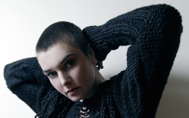 person with shaved head in sweater