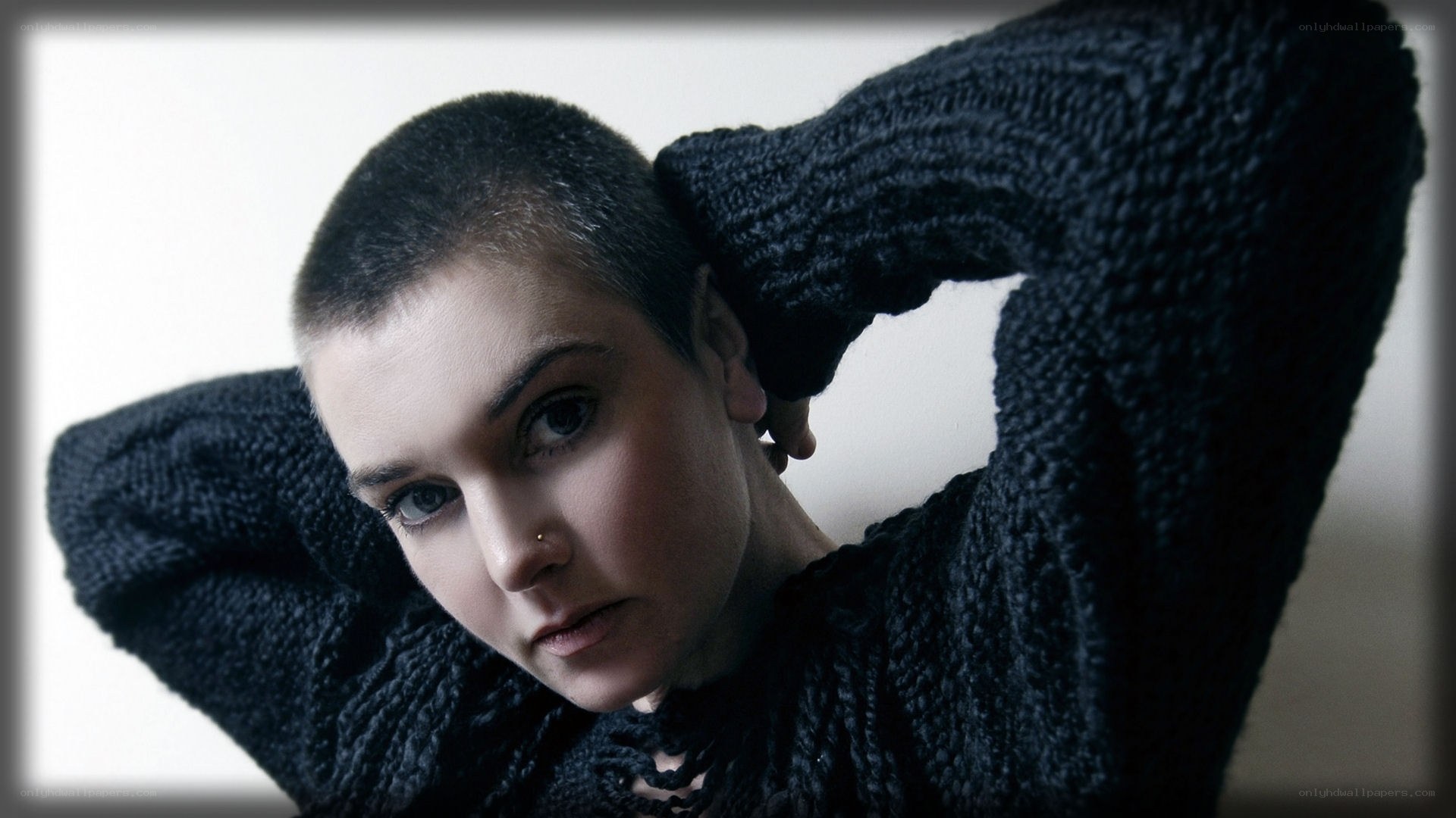 person with shaved head in sweater
