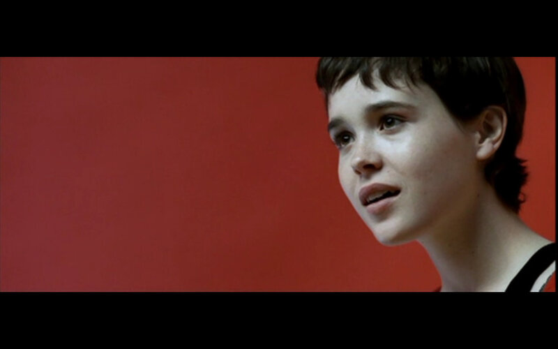 person with short hair against red wall