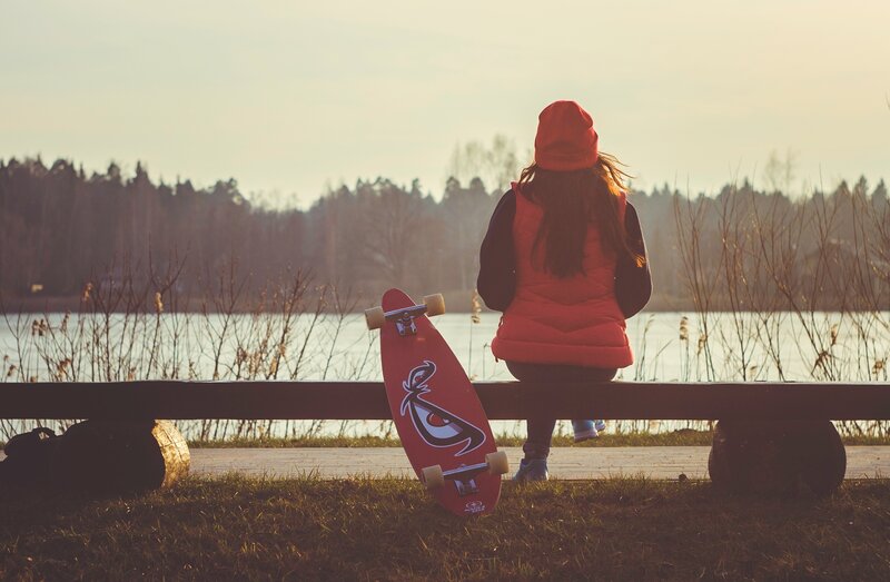 Person with skateboard by lake