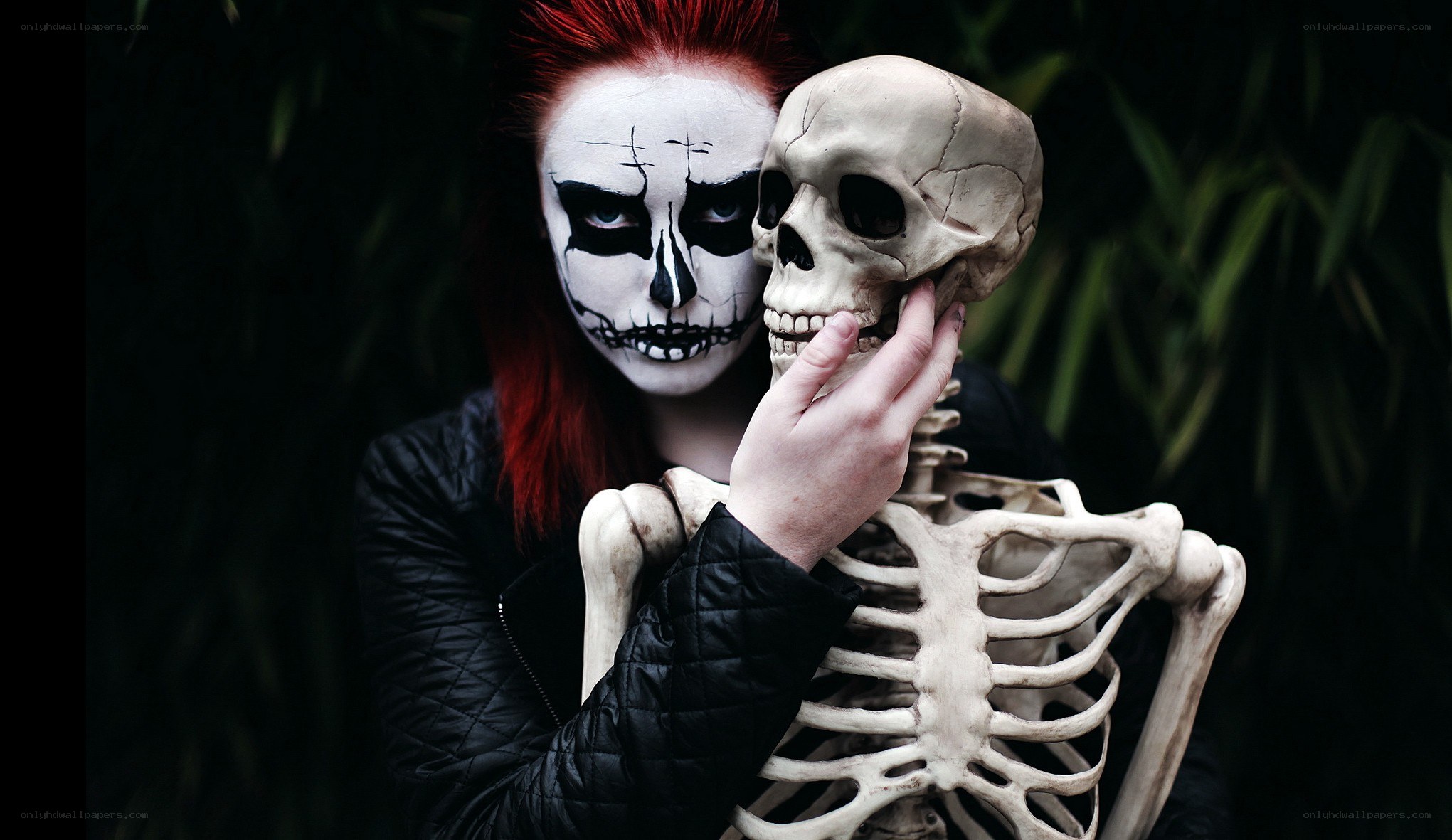 person with skull makeup holding skeleton