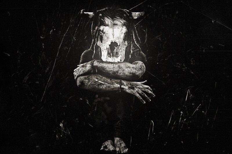 person with skull mask in dark field