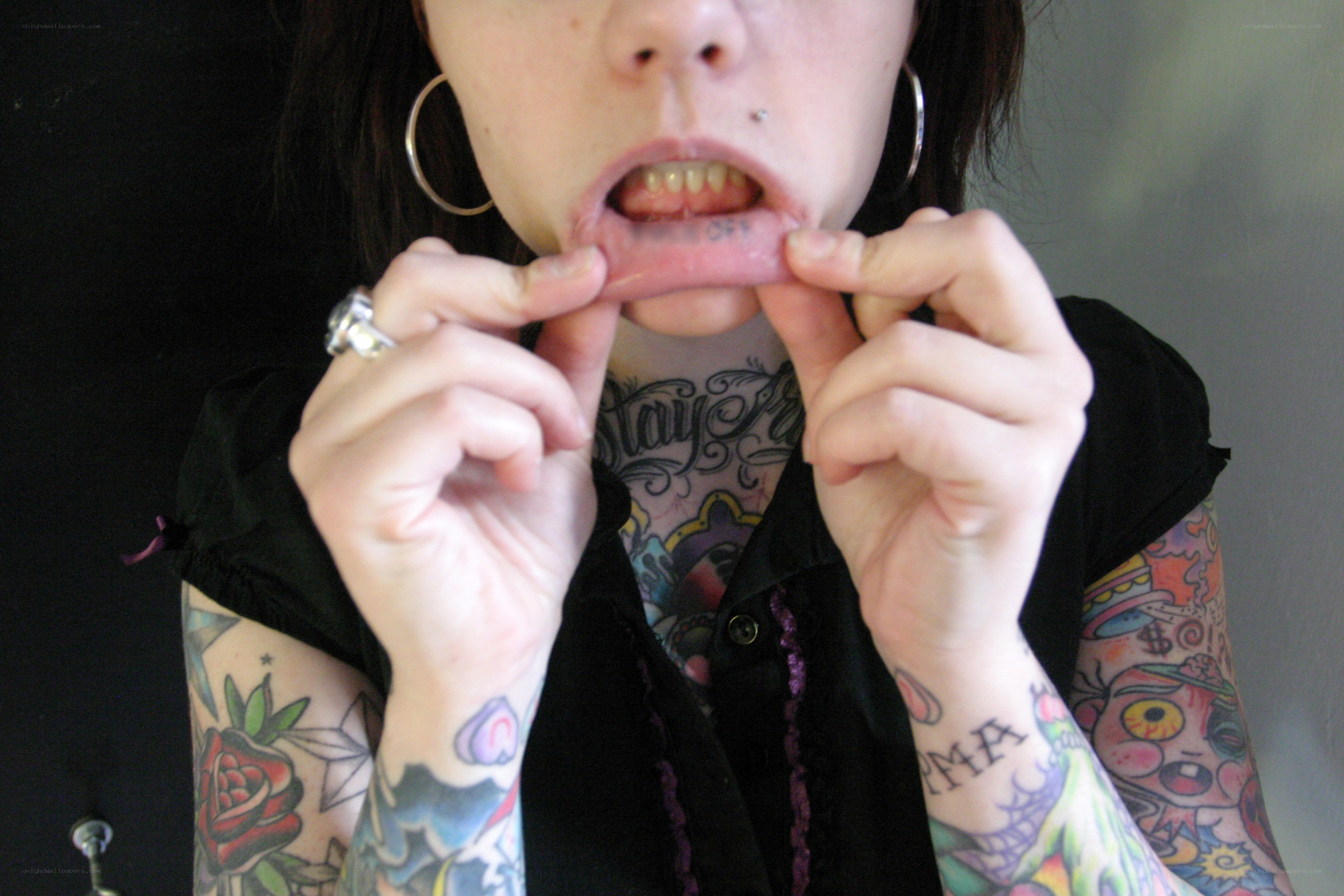 person with tattoos showing lip piercing