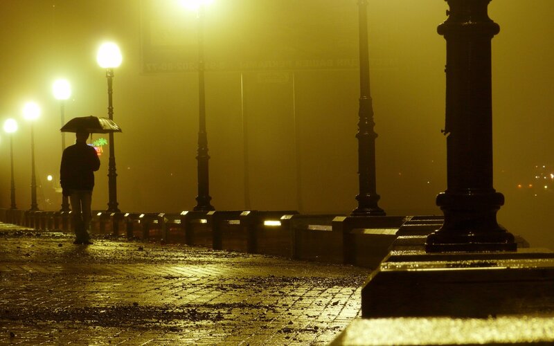 Person with umbrella in foggy night
