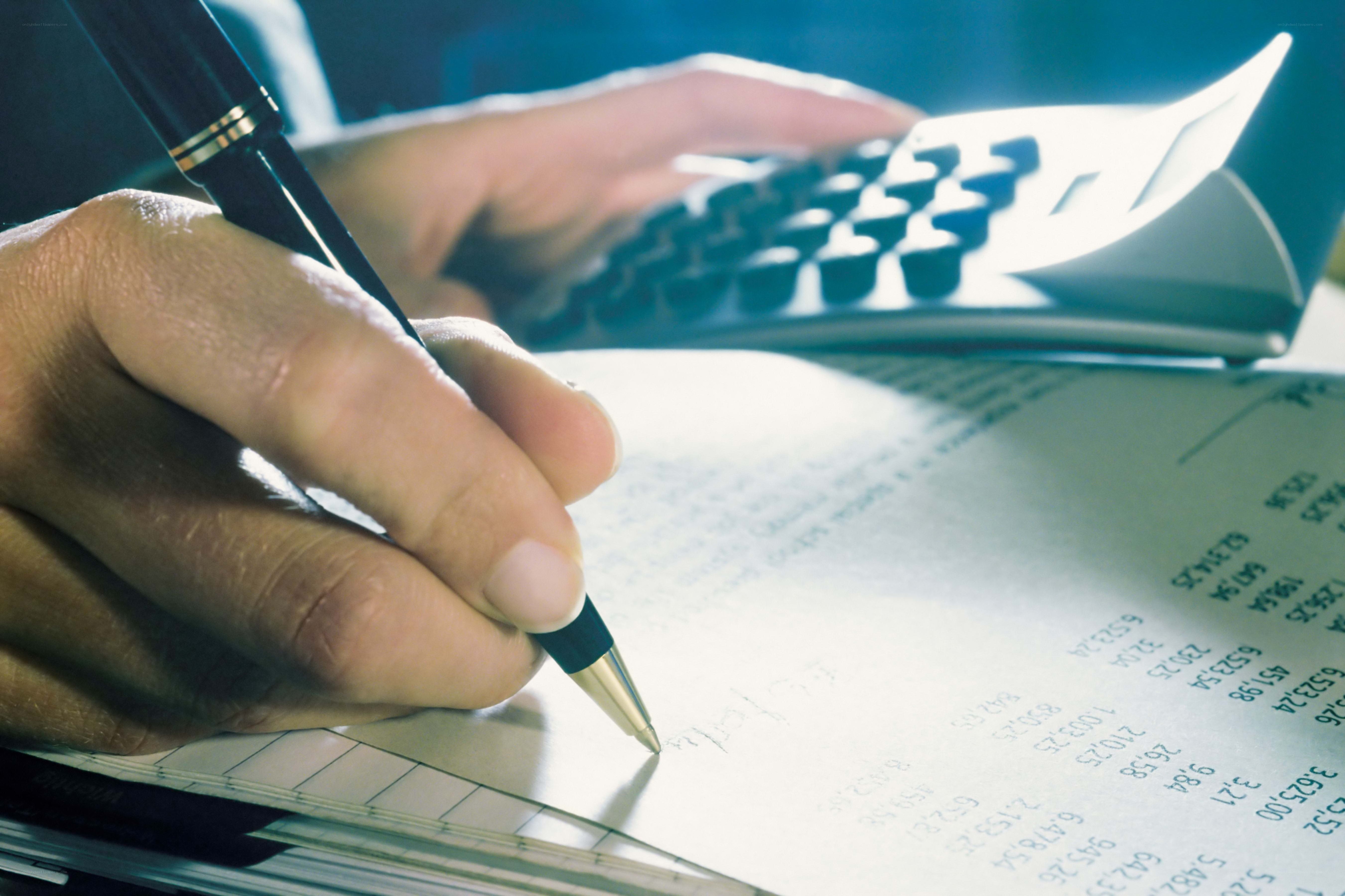 person writing with pen and calculator