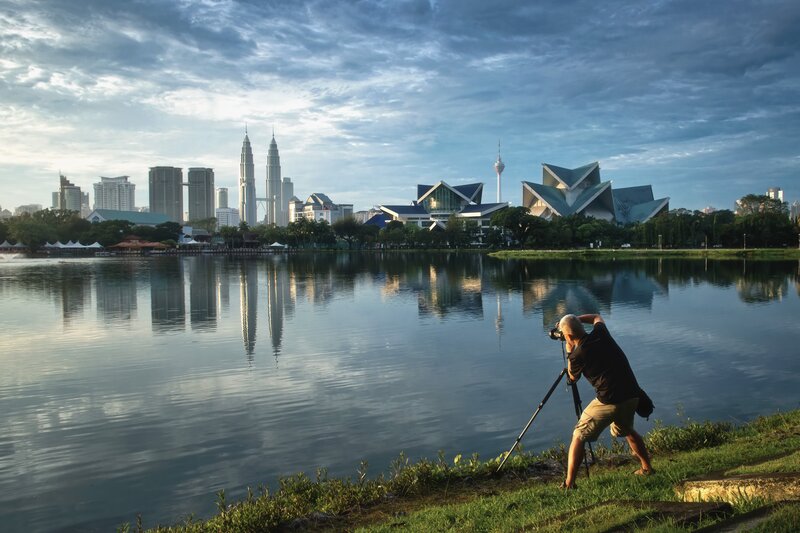 Photographer at lake with city skyline