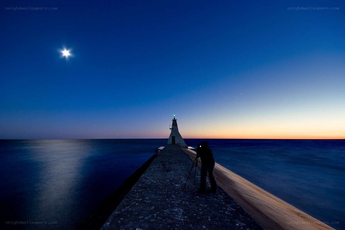 Photographer at pier with moon