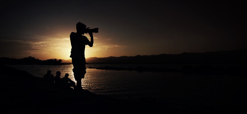 Photographer at sunset by the water