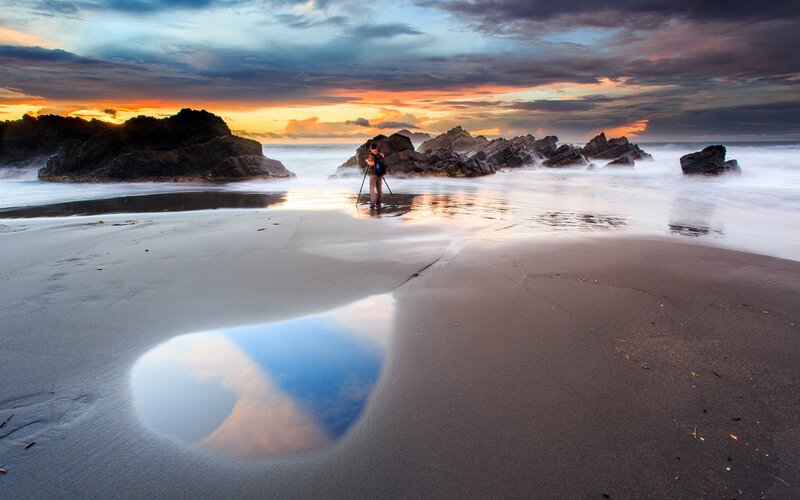 Photographer at sunset on a rocky beach